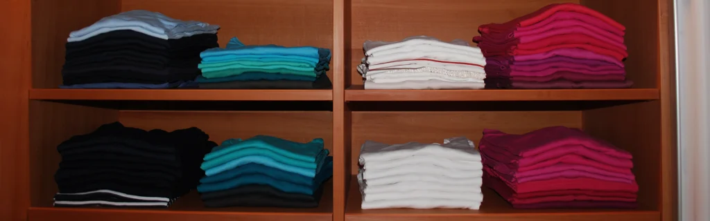 Kleiderschrank mit verschiedenen T-Shirts, farblich sortiert.